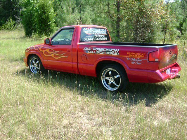 A red truck with flames painted on the side is parked in a grassy field.