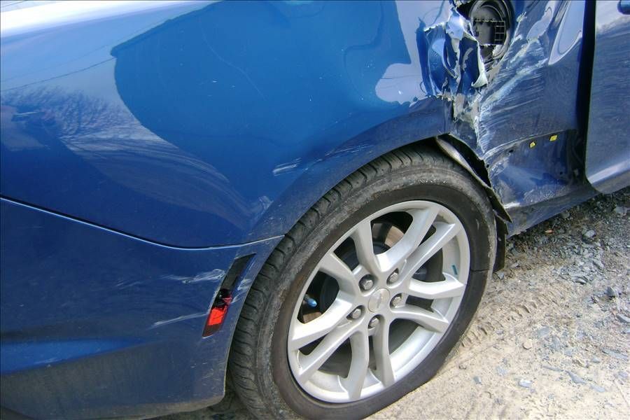 A blue car with a damaged fender and tire