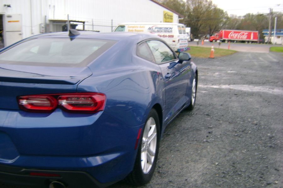A blue car is parked in front of a coca cola truck