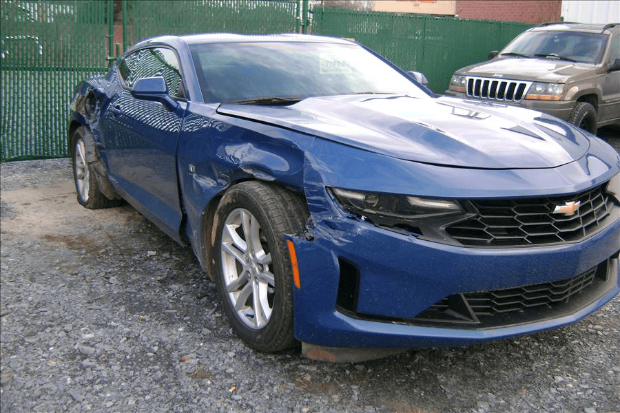 A blue chevrolet camaro is parked in a gravel lot.