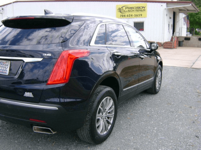 A black car is parked in front of a building that says precision auto repair