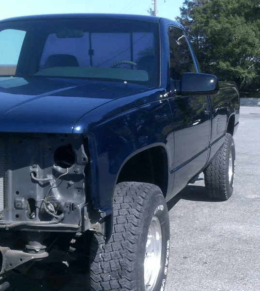 A blue truck is parked on the side of the road.
