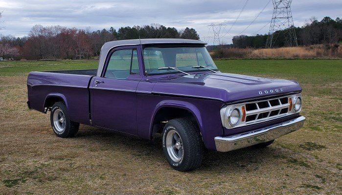 A purple truck is parked in a grassy field.