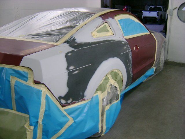 A red car is covered in blue and white tape