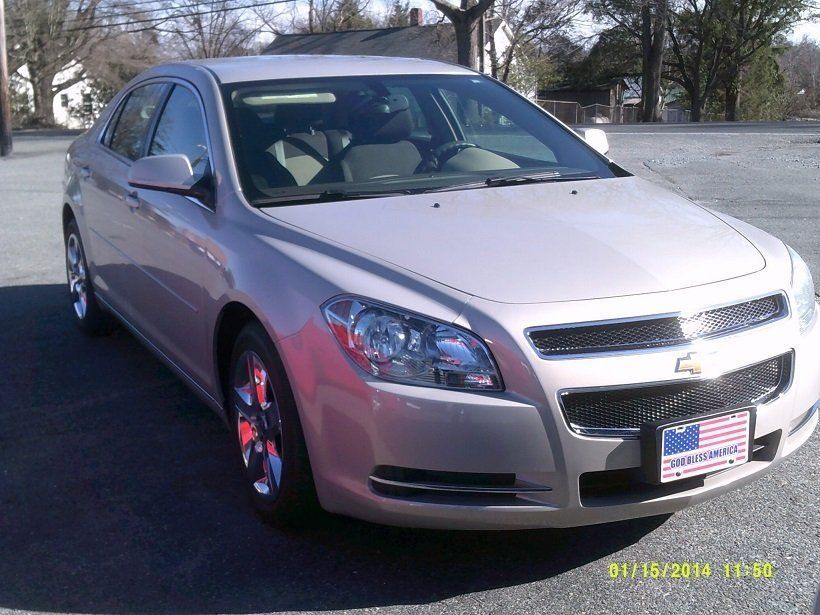 A silver chevrolet malibu is parked in a parking lot