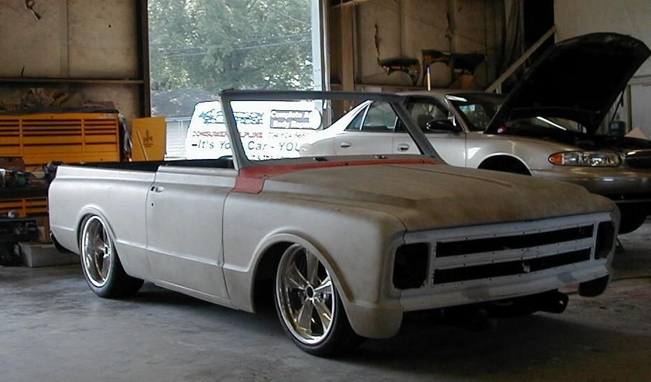 A white truck with the hood up is parked in a garage