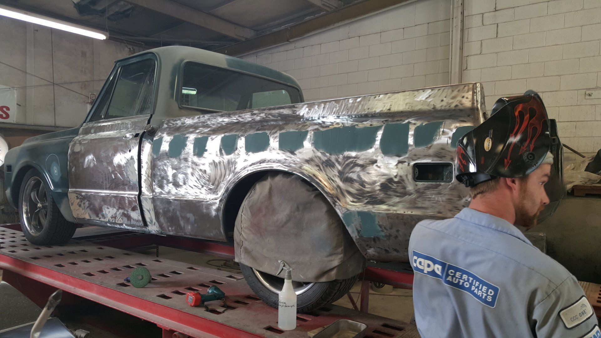 A man is welding a truck in a garage.