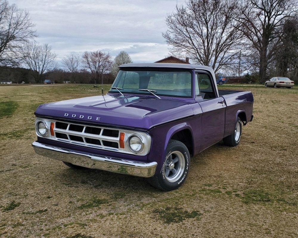 A purple dodge truck is parked in a grassy field.