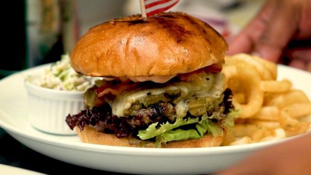 A hamburger and french fries are on a white plate.