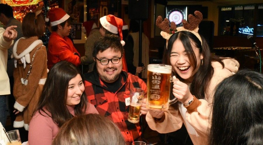 一群の人々がビールのグラスを持ってテーブルに座っている。