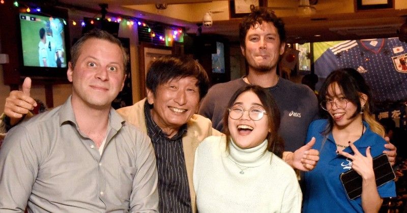 A group of people from several different nations are posing for a picture in a sports bar in Nagoya.