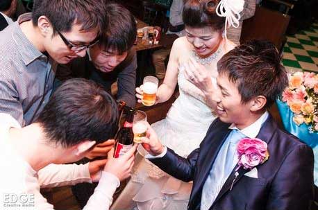 名古屋のスポーツバーで行われた結婚式の披露宴で、新郎新婦に乾杯している人々のグループ