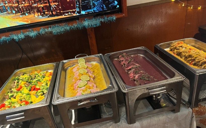 A buffet table with three trays of food on it.