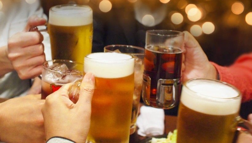 A group of people are toasting with beer glasses at a table.