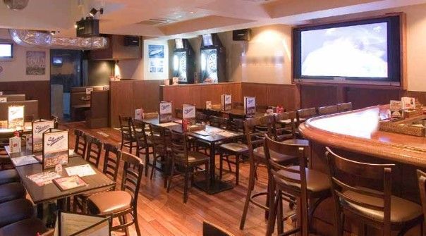 Rental space in a restaurant with tables and chairs and a large screen on the wall for presentations.