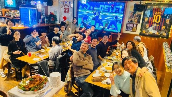 A group of people are sitting at tables in a sports bar watching American Football.