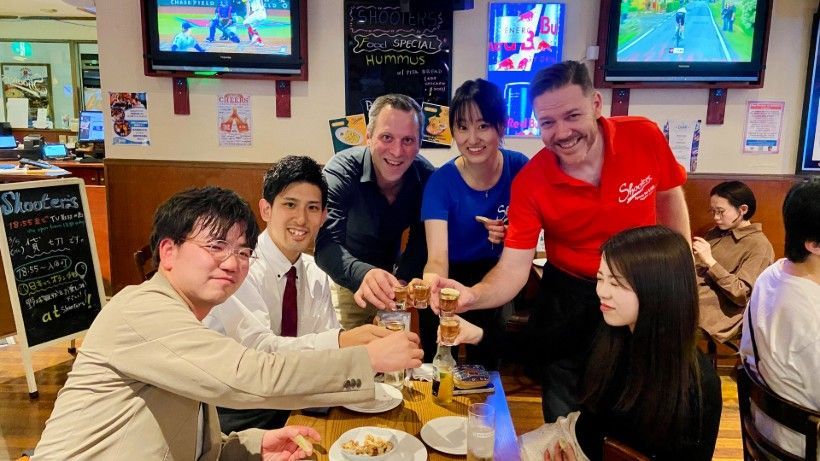 A group of people are sitting at a table in a restaurant toasting with tequila.