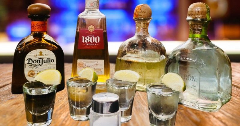 A table topped with bottles of tequila and shot glasses.