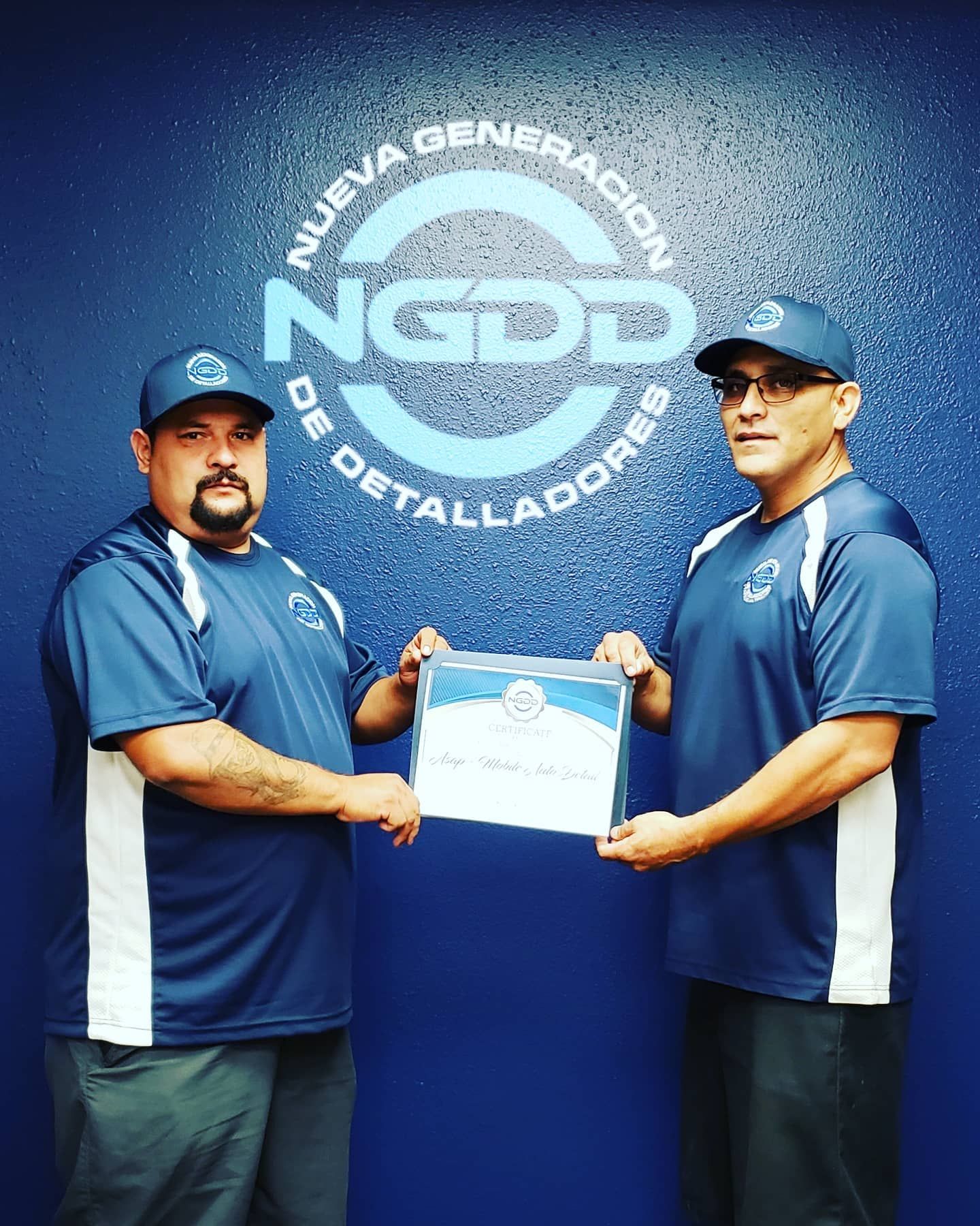 Two men holding a certificate in front of a ngdd logo