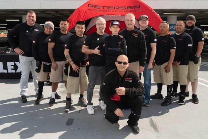 A group of men are posing for a photo in front of a peterson tent