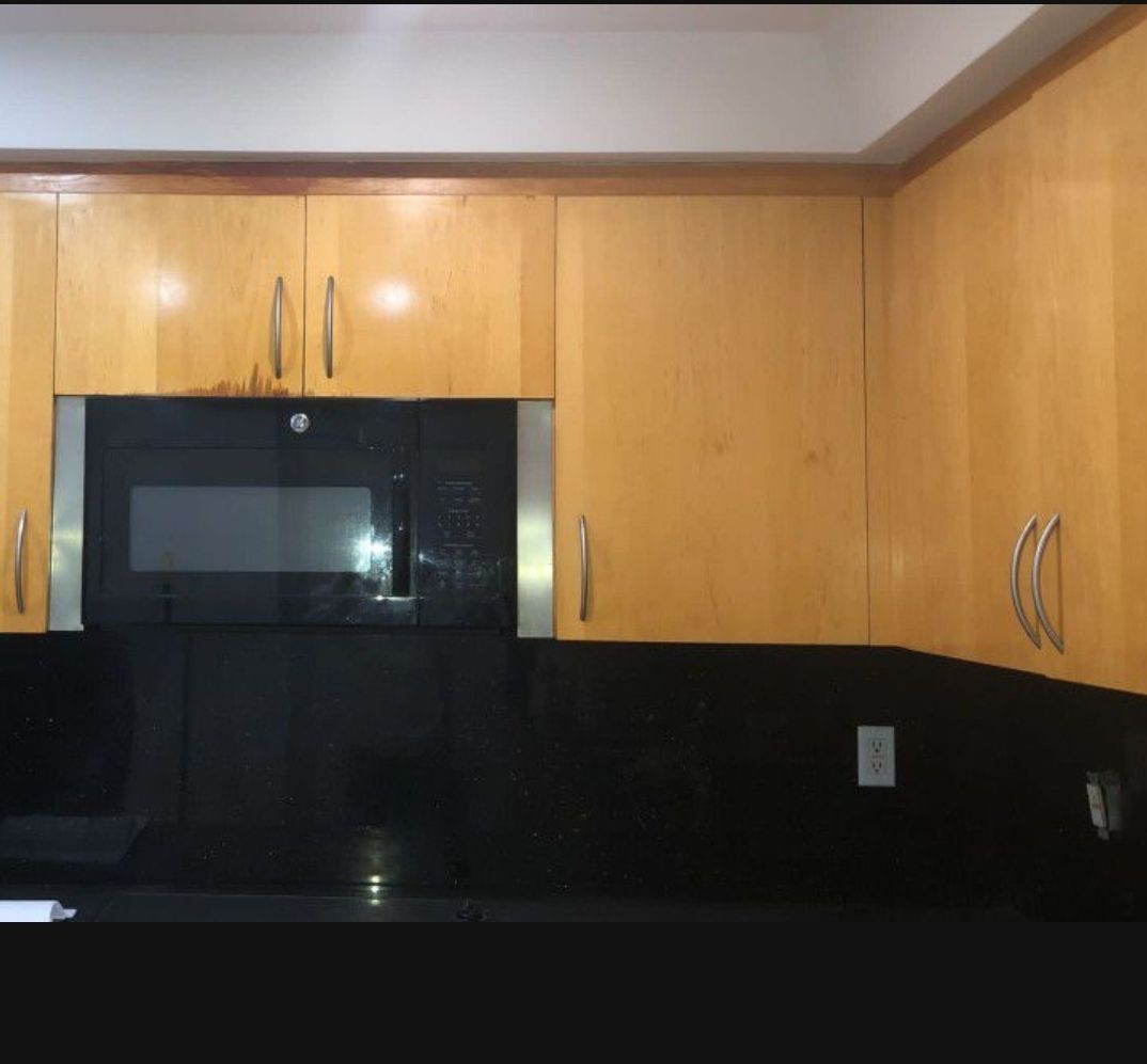 a kitchen with wood cabinets and a black microwave