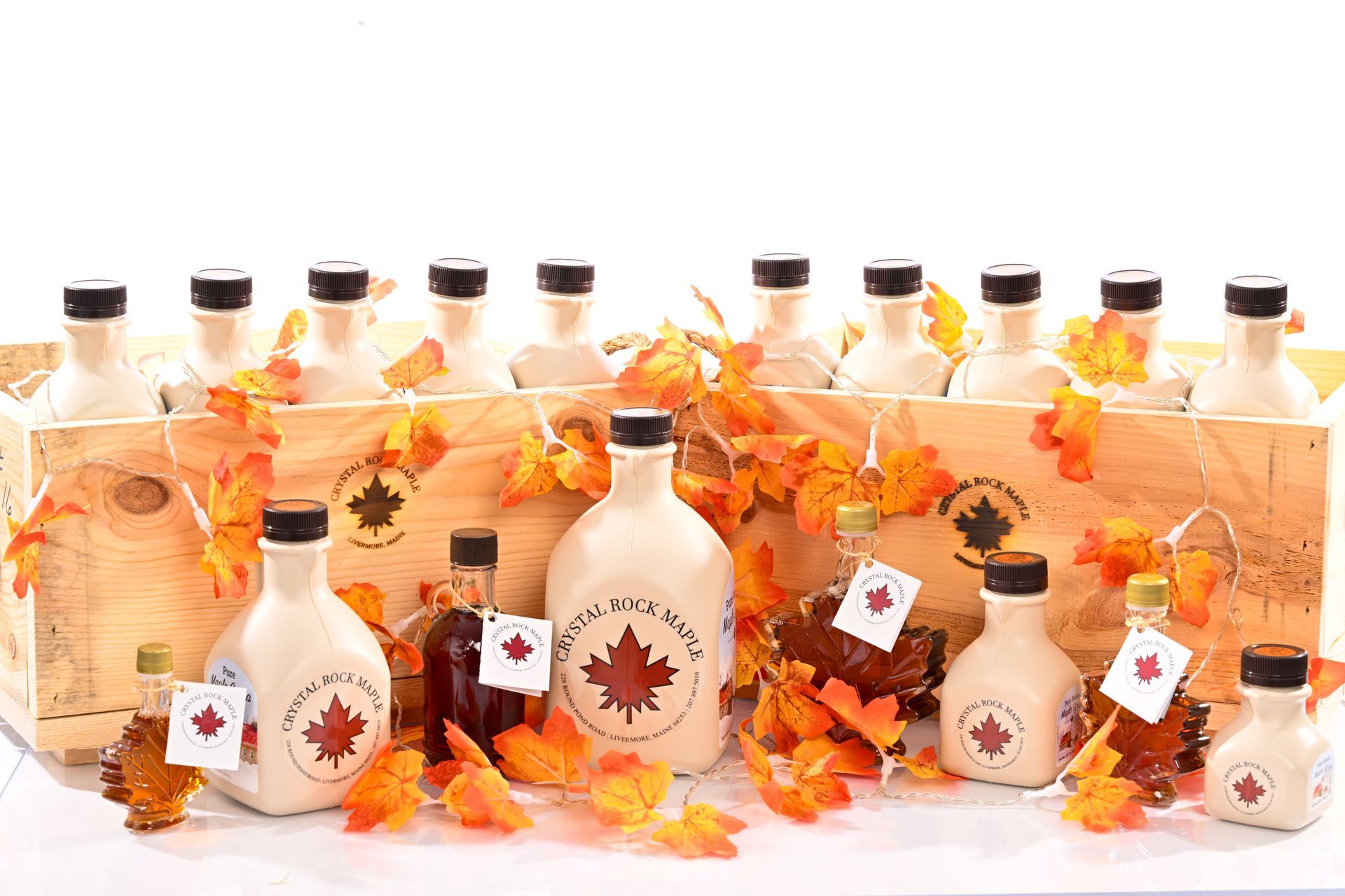Maple syrup bottles in wooden crates, with orange autumn leaves.