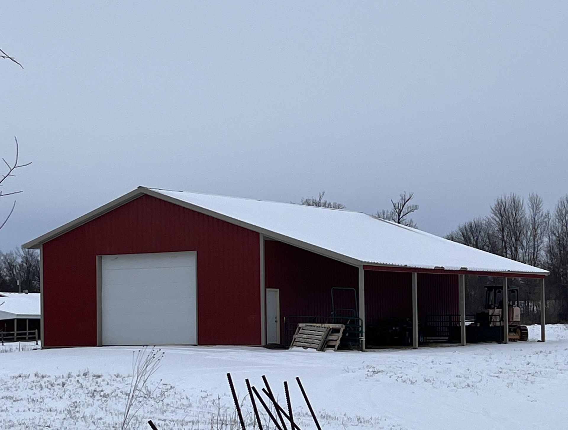 A red barn with a white roof is covered in snow.