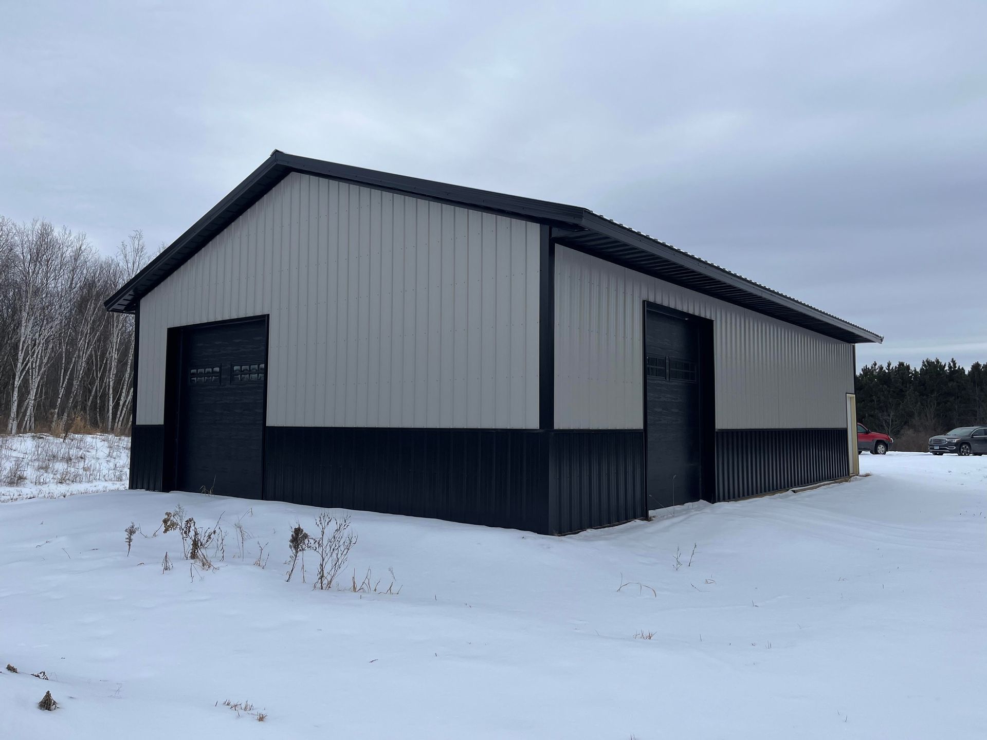 A large metal building is sitting in the middle of a snow covered field.