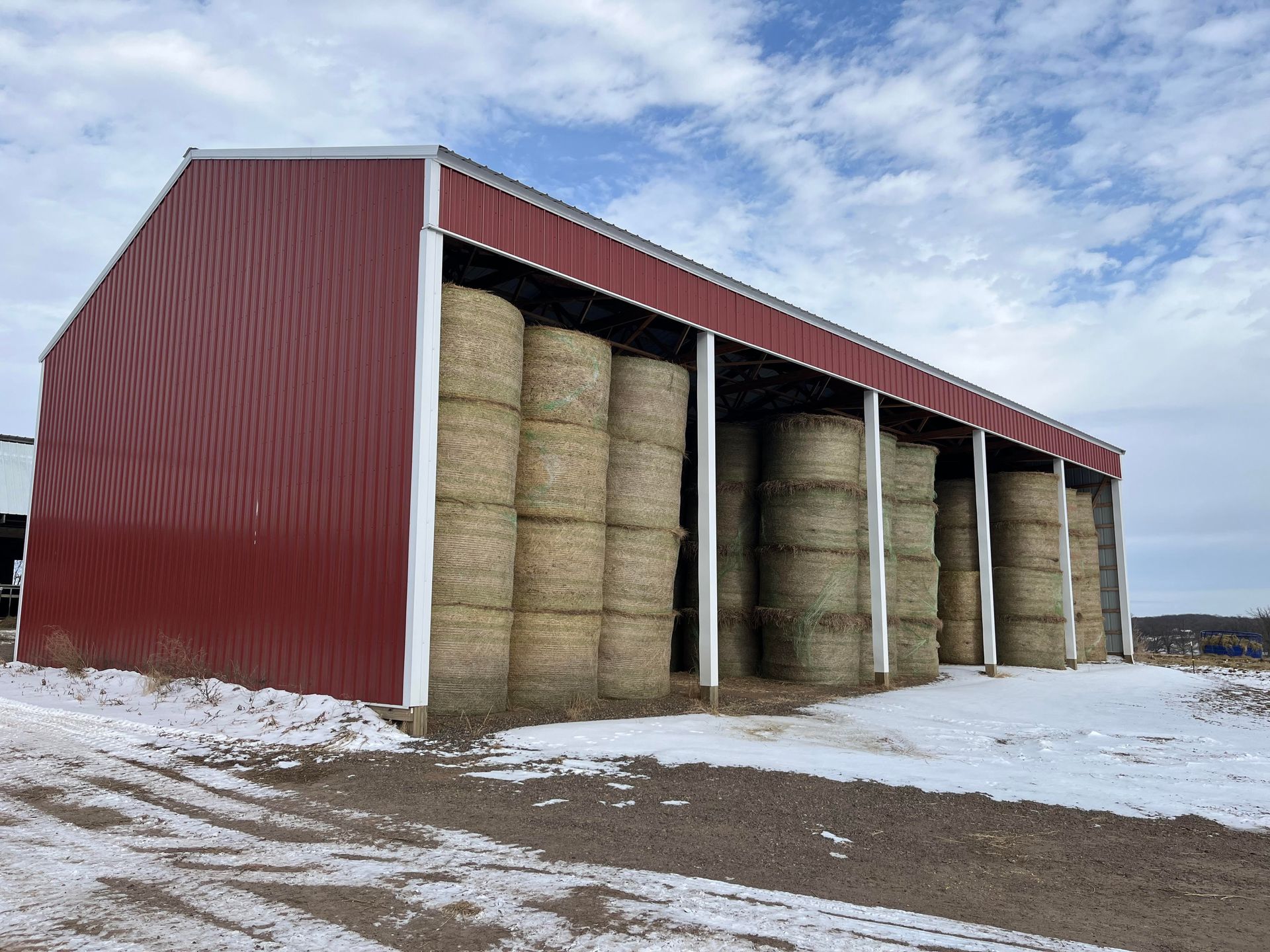 A barn filled with hay bales in the snow.