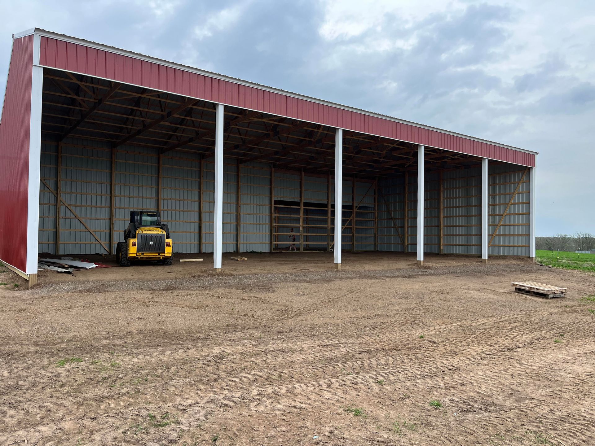 A yellow and black tractor is parked in front of a large building.