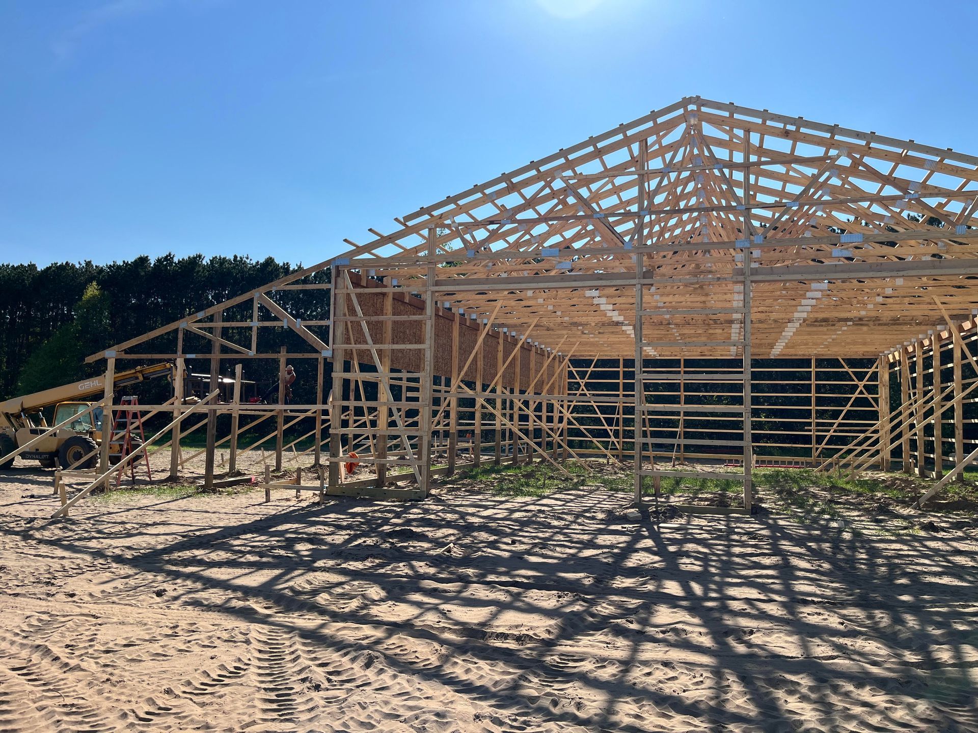 A large wooden structure is being built on a dirt field.