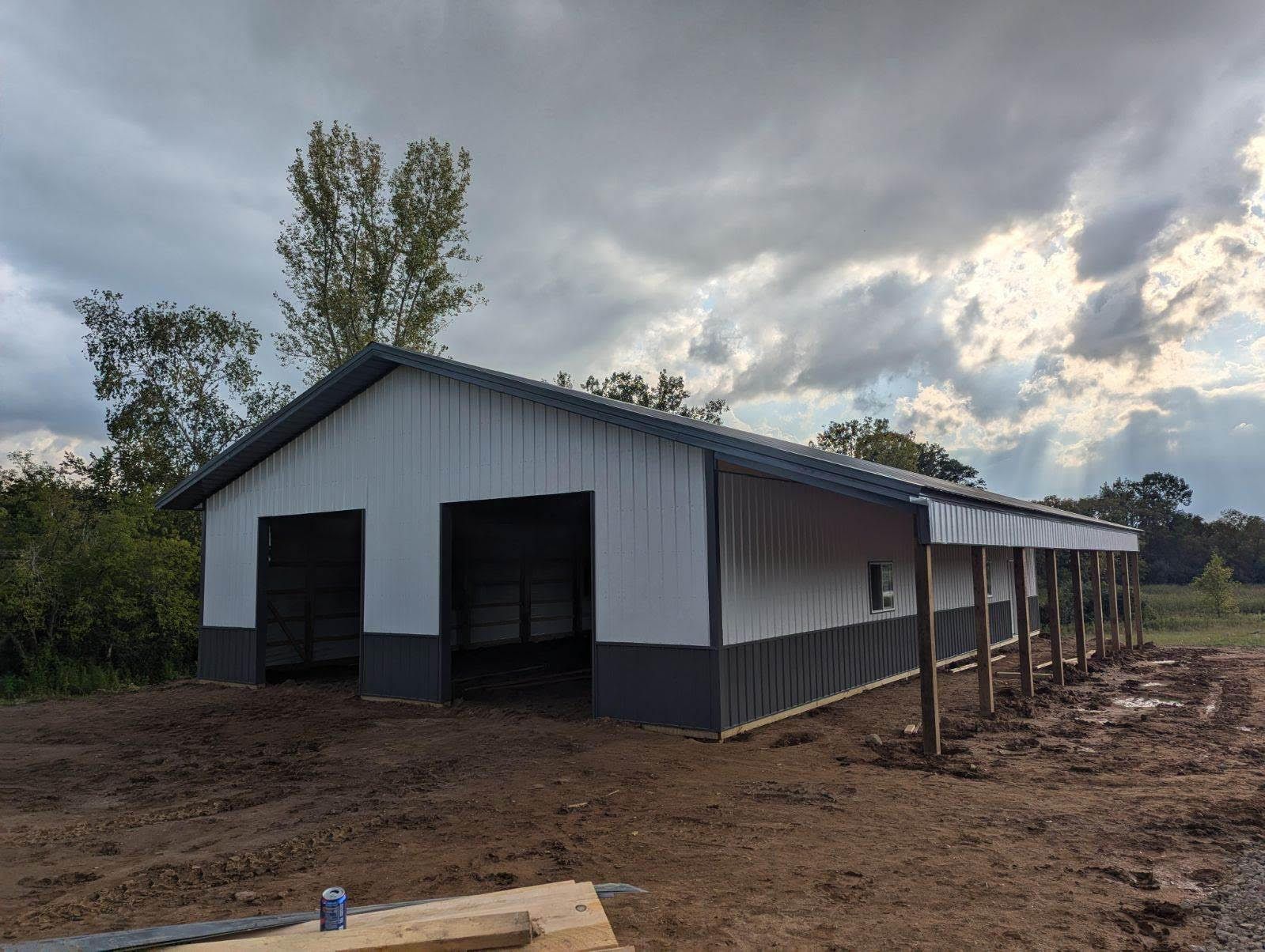 A large white and gray building is sitting in the middle of a dirt field.