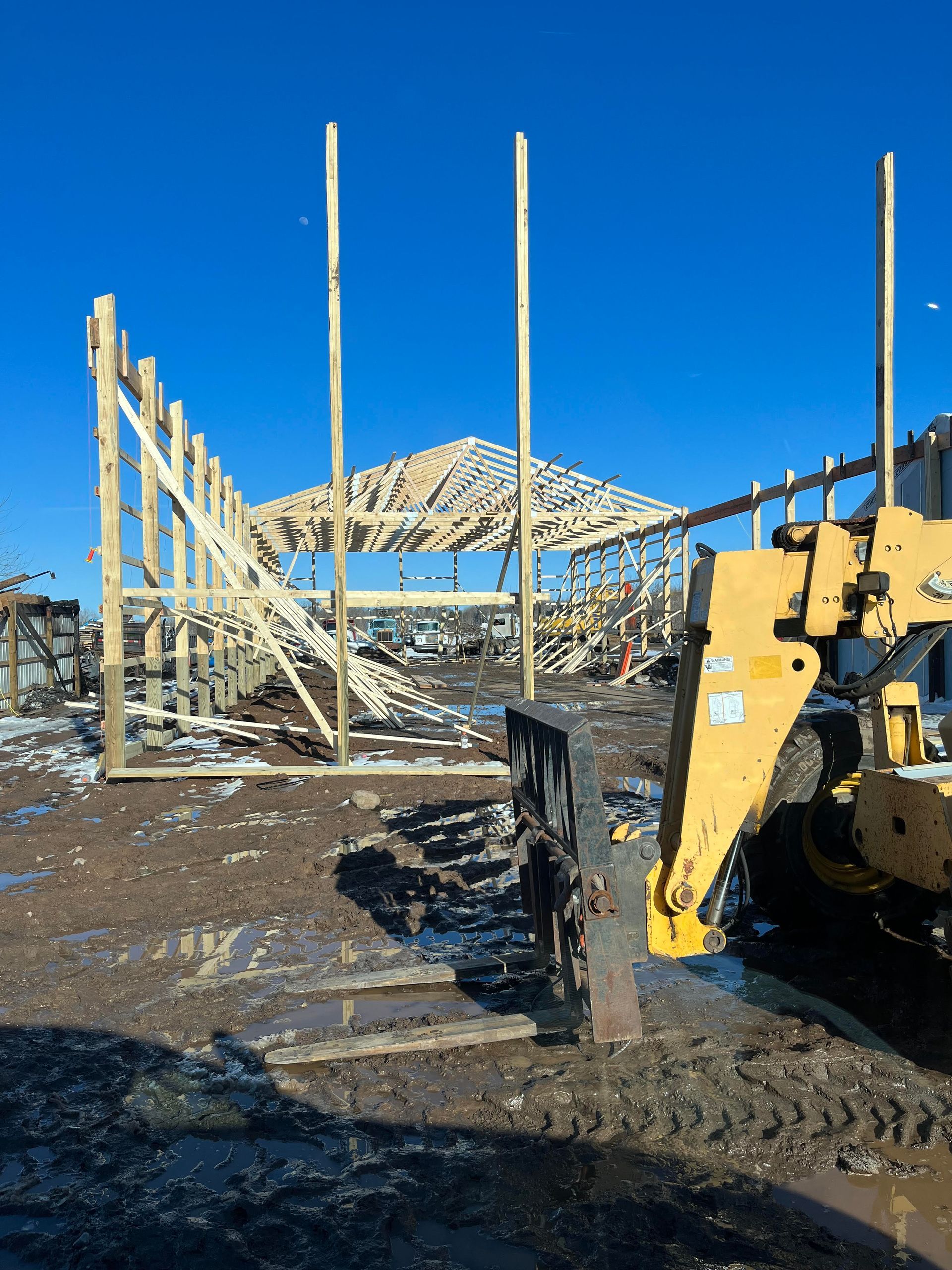 A yellow bulldozer is parked in front of a building under construction