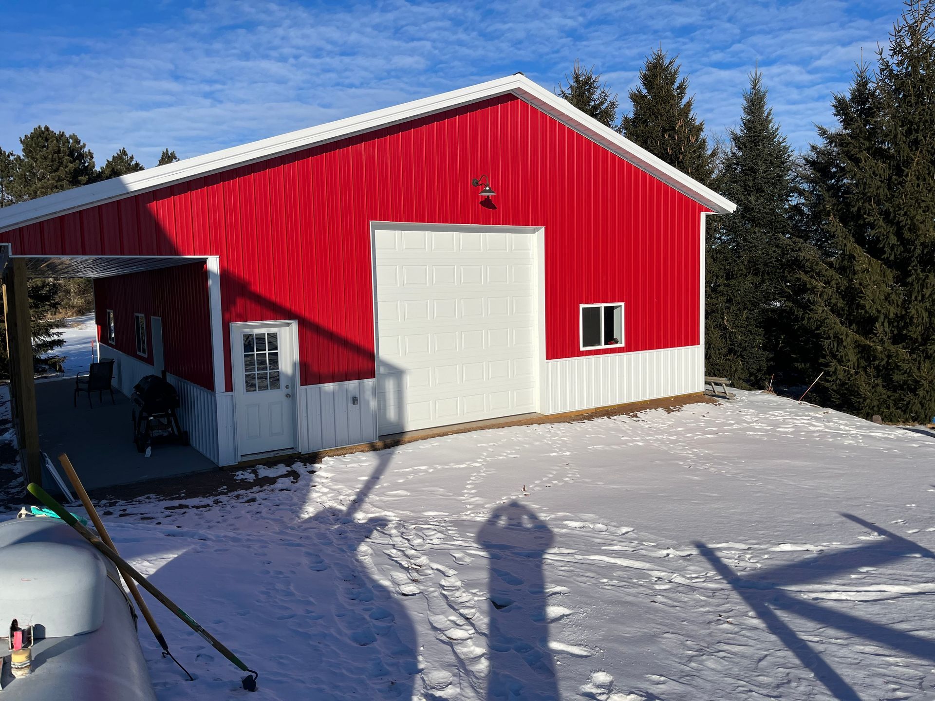 A red and white barn is sitting on top of a snow covered hill.
