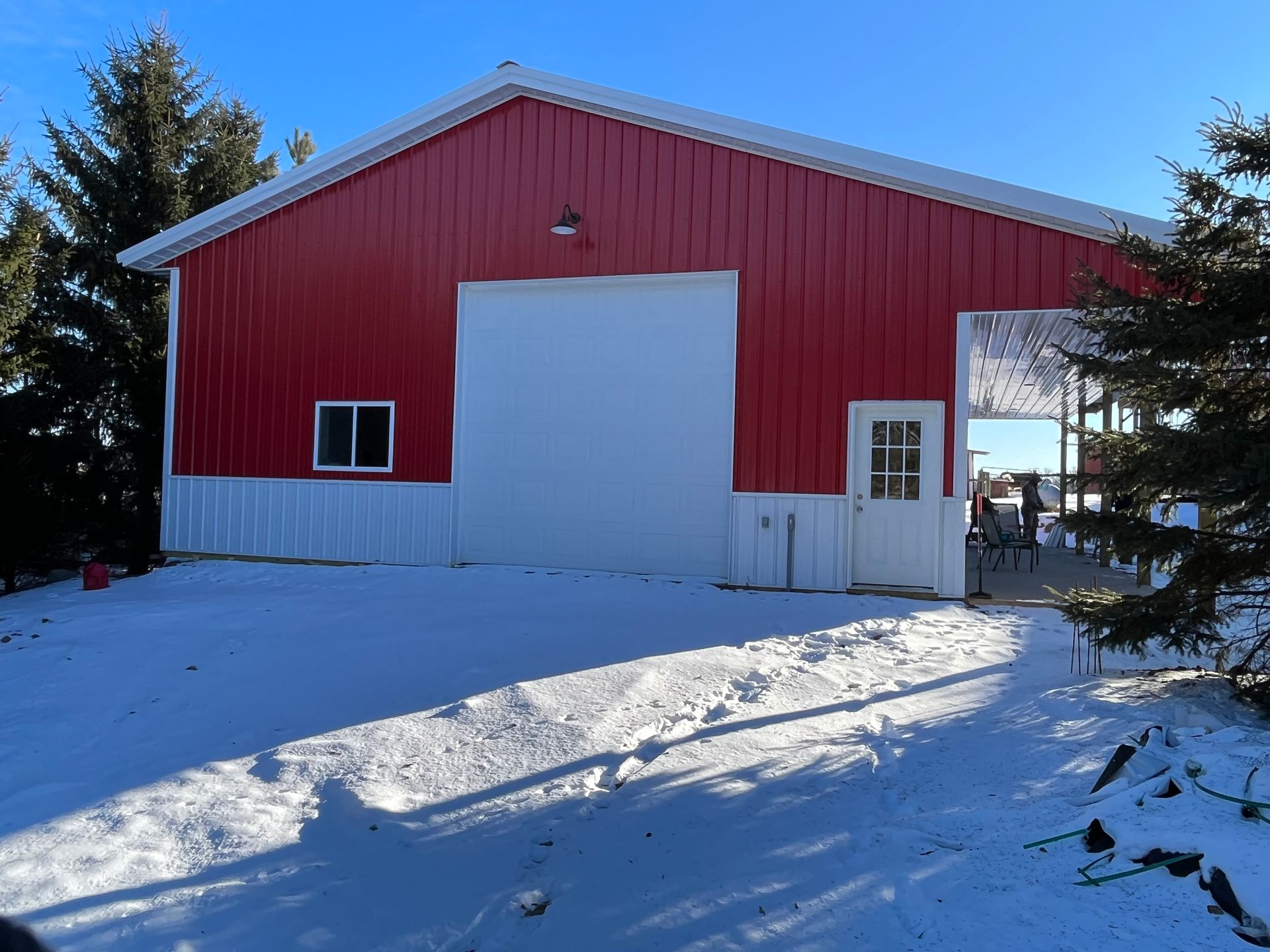 A red and white barn is sitting in the middle of a snowy field.