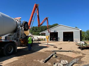 A man is standing in front of a concrete mixer truck.