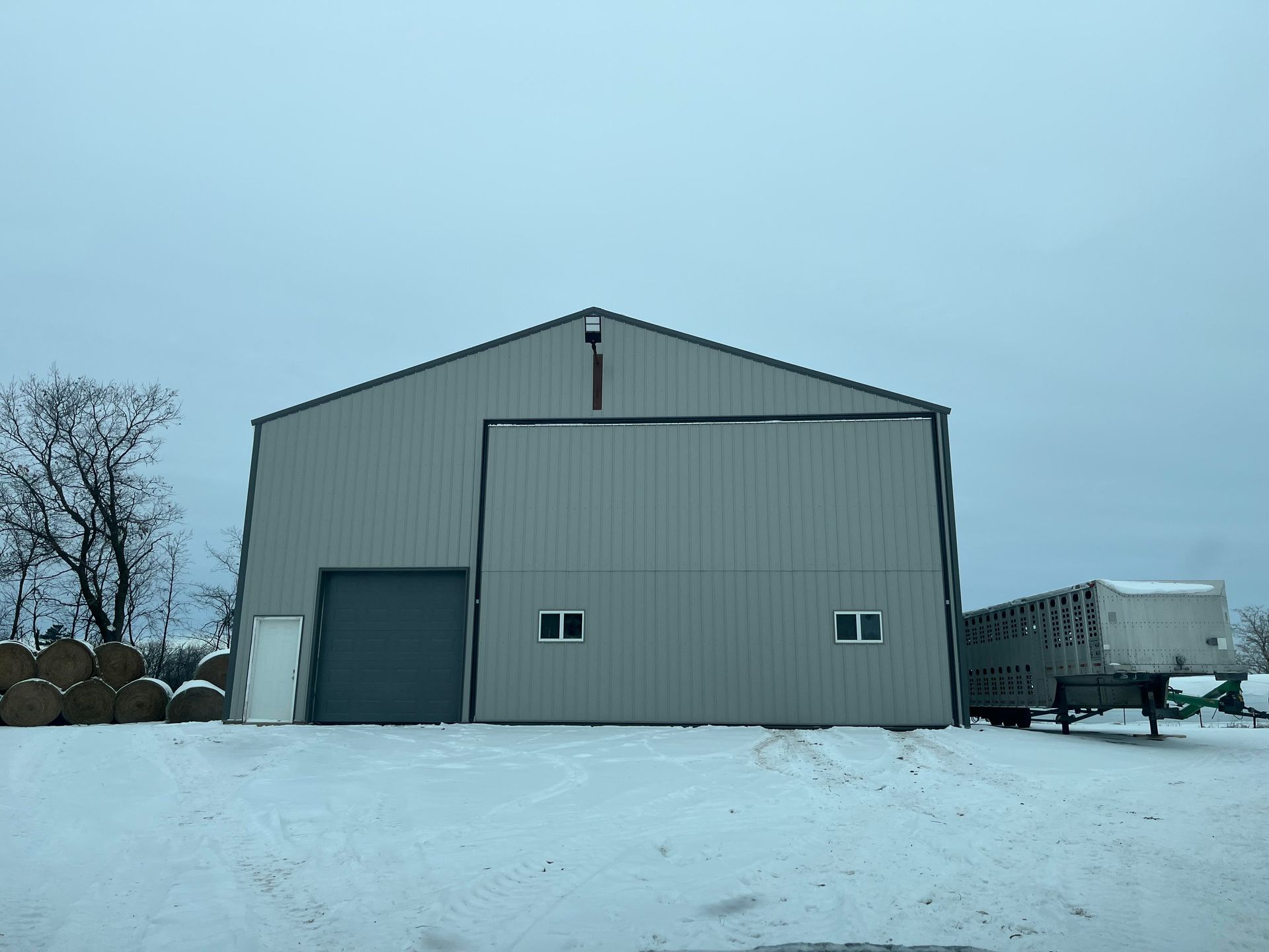 A large building with a sliding door is sitting in the snow.