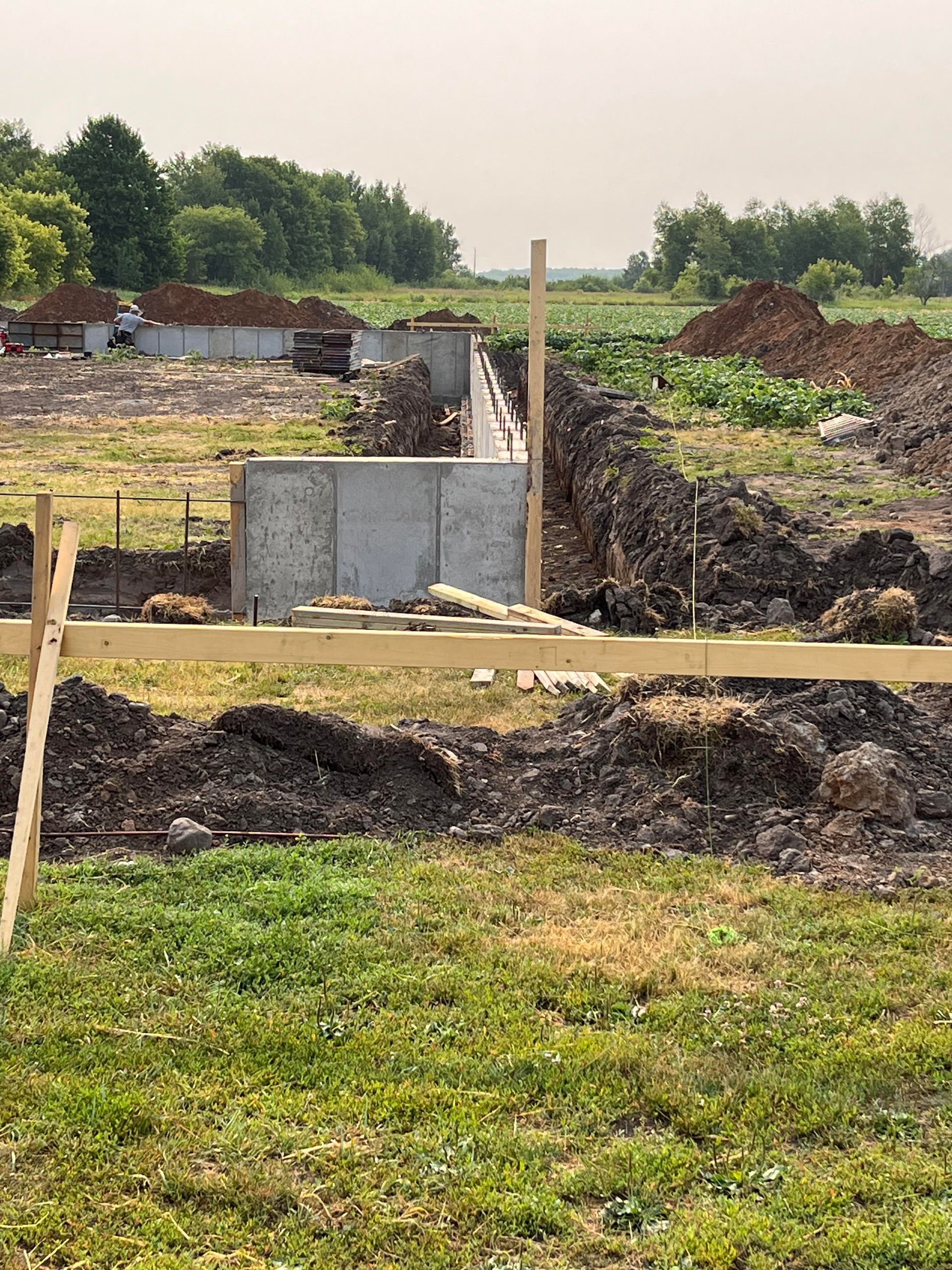 A construction site with a wooden fence in the middle of a grassy field.