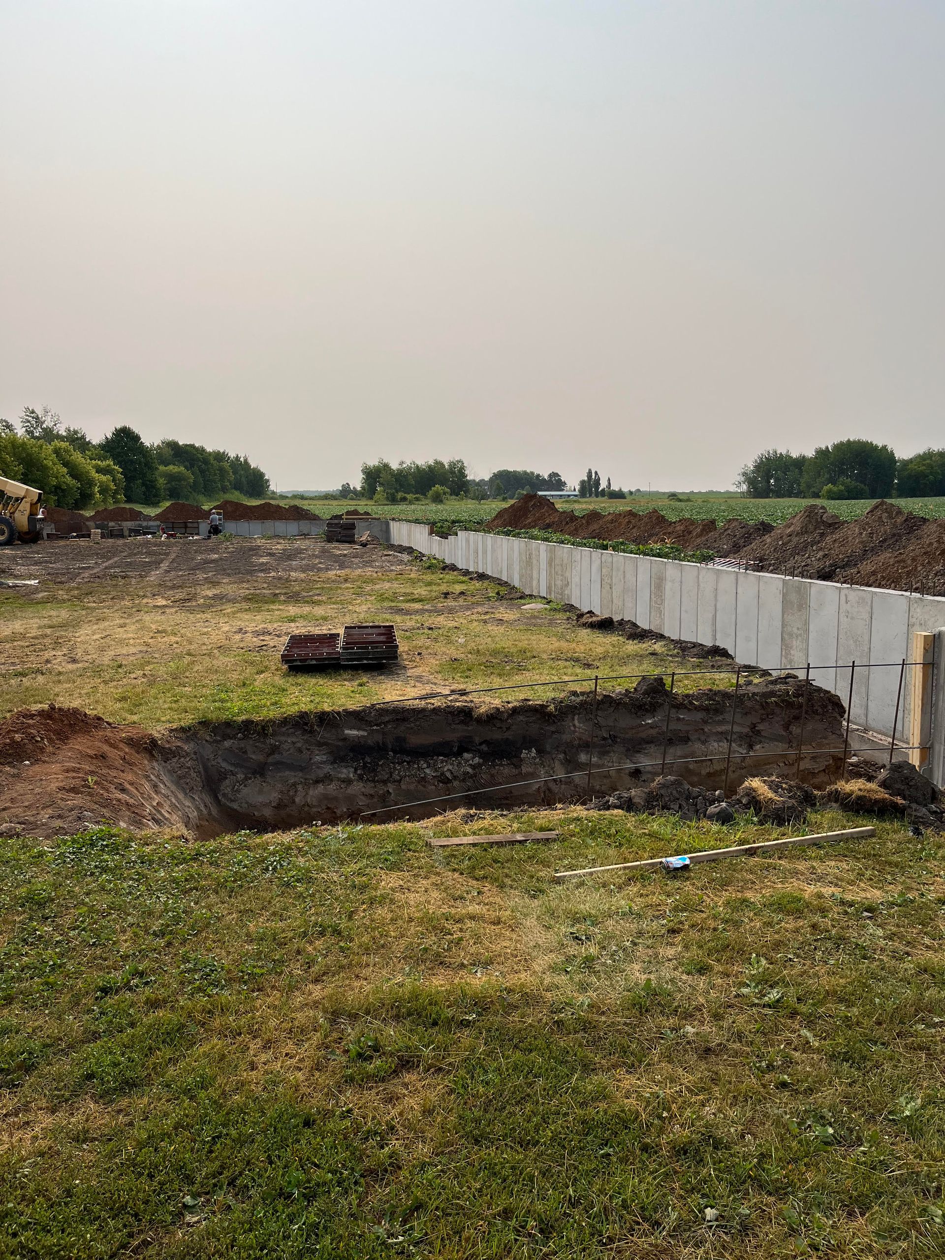 A large hole in the middle of a grassy field next to a fence.