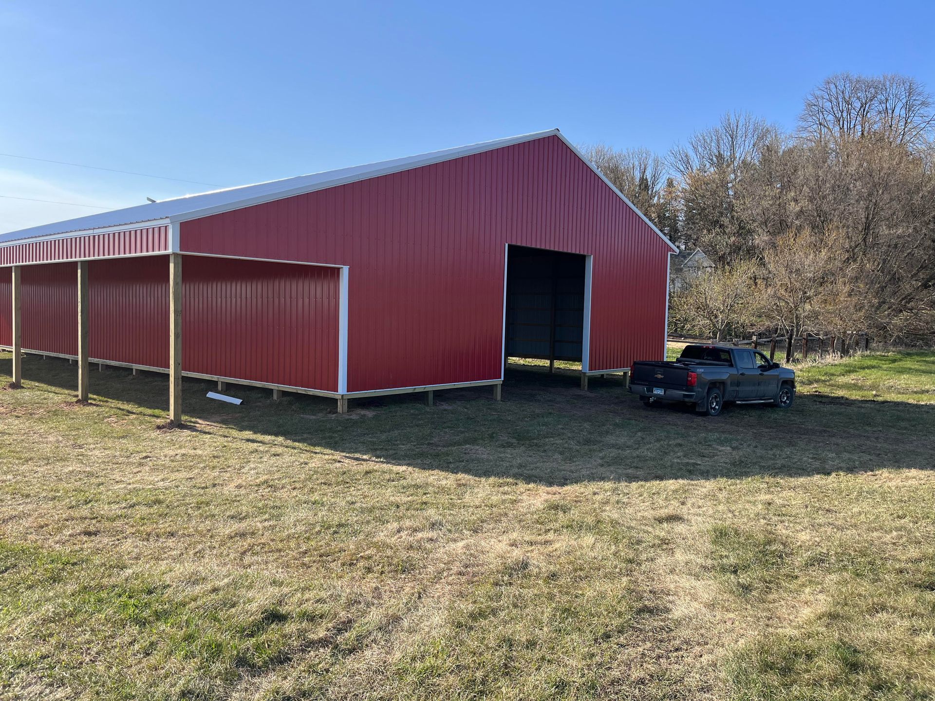 A red barn with a truck parked in front of it.