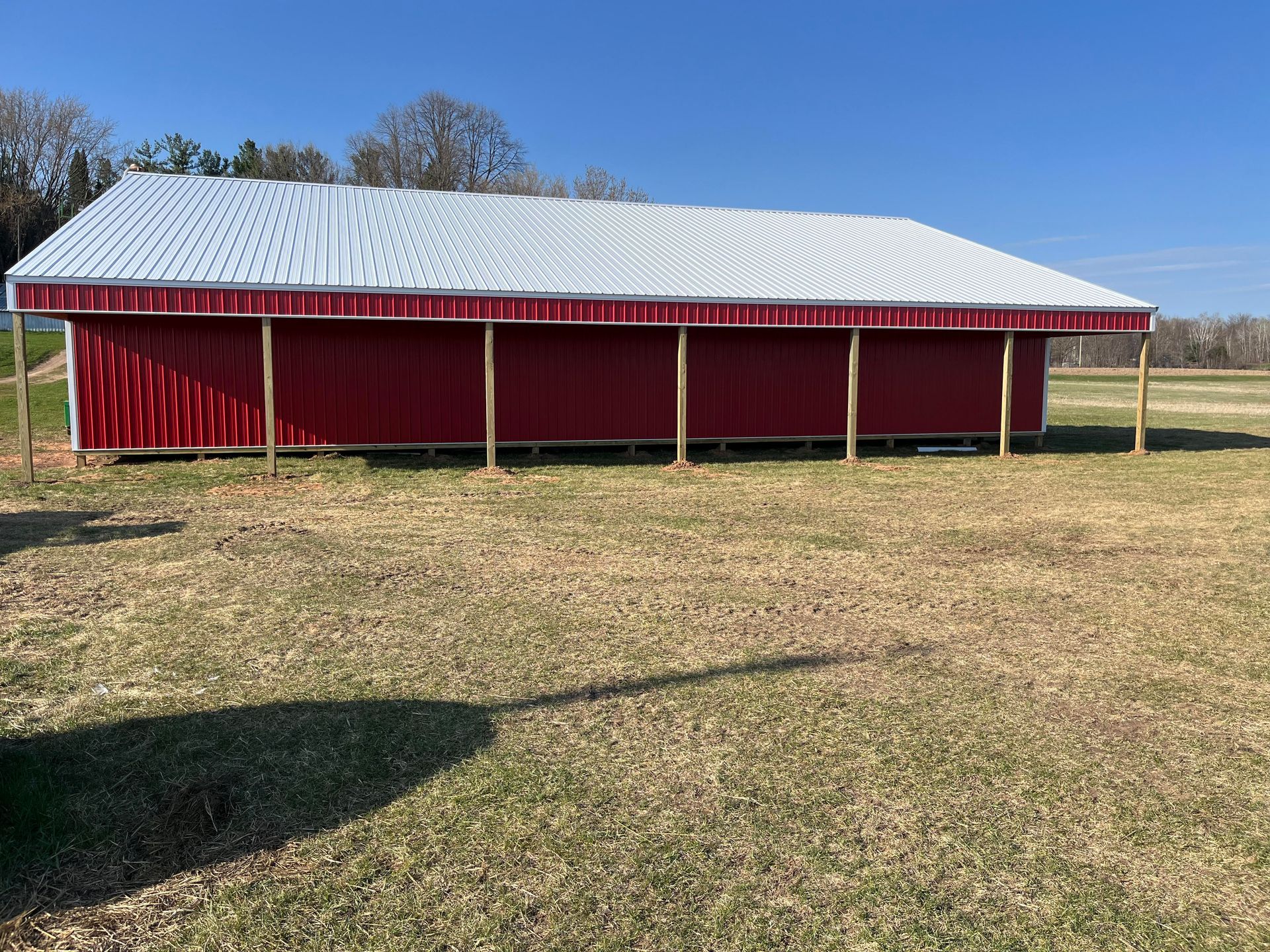 A red barn with a white roof is sitting in the middle of a grassy field.