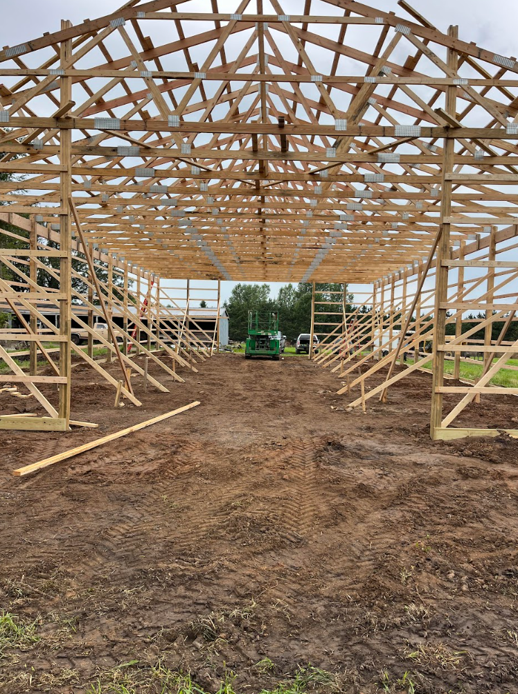 A large wooden structure is being built in a dirt field.