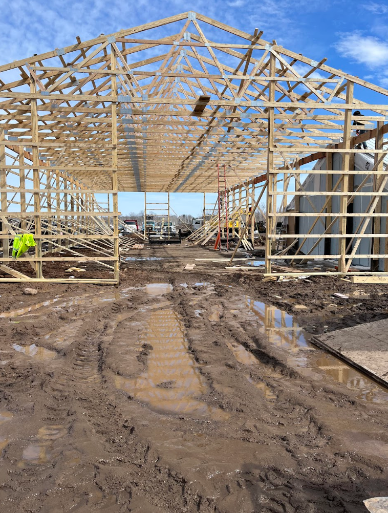 A large wooden structure is being built in a muddy field.