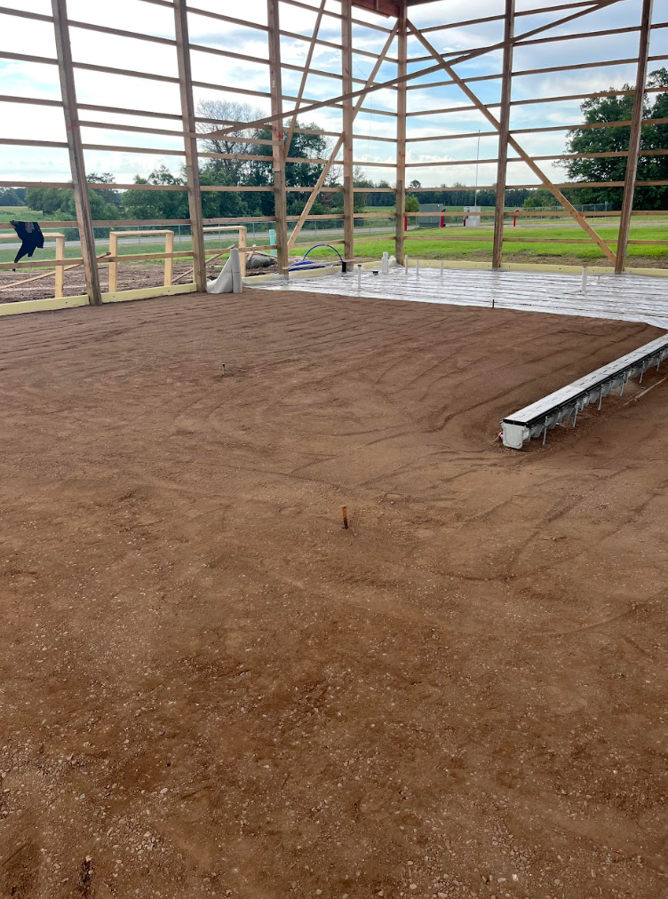 A large wooden building with a dirt floor and a railing.