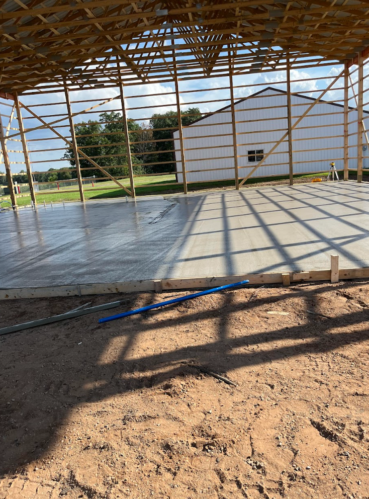 A building under construction with a concrete floor and a wooden roof.