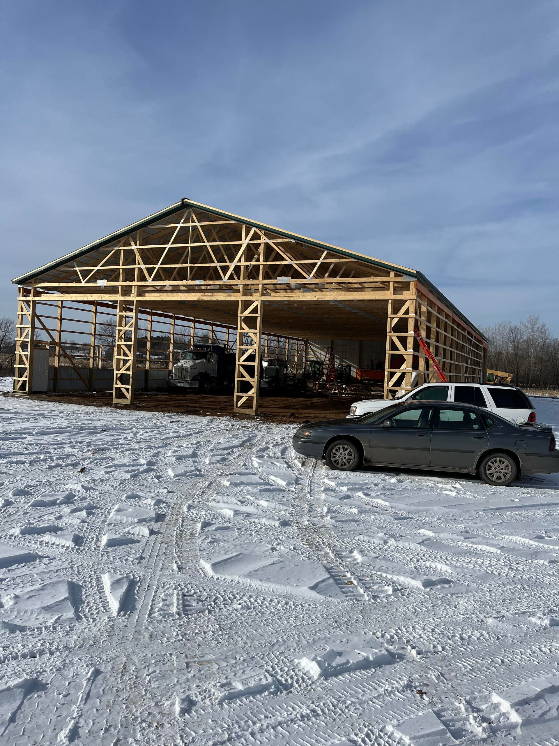 A car is parked in front of a building under construction in the snow.