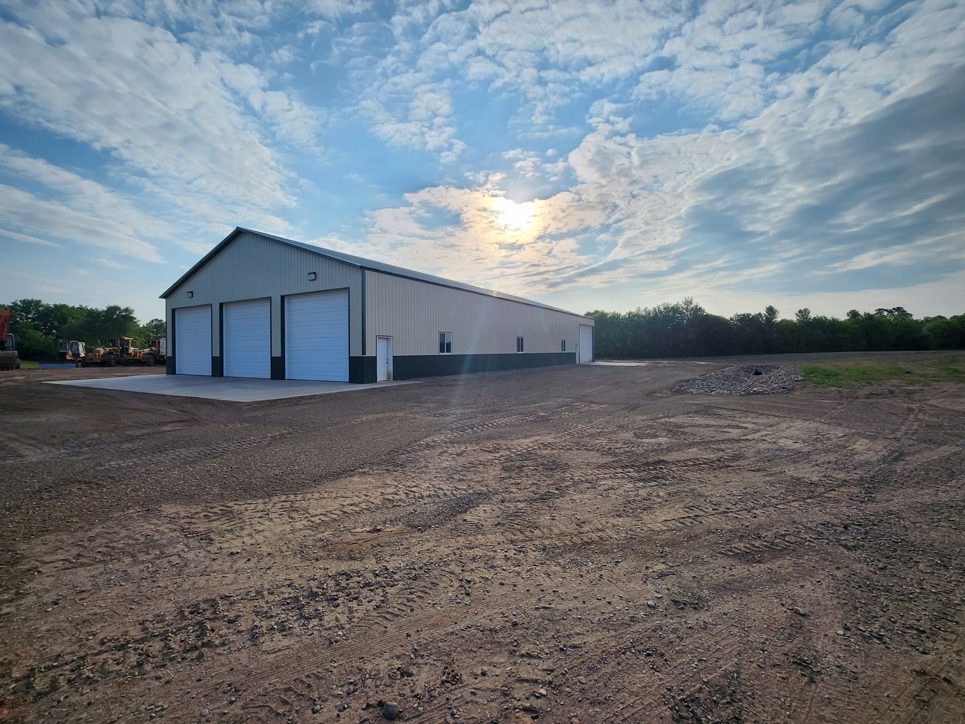 A large building with white doors is sitting in the middle of a dirt field.