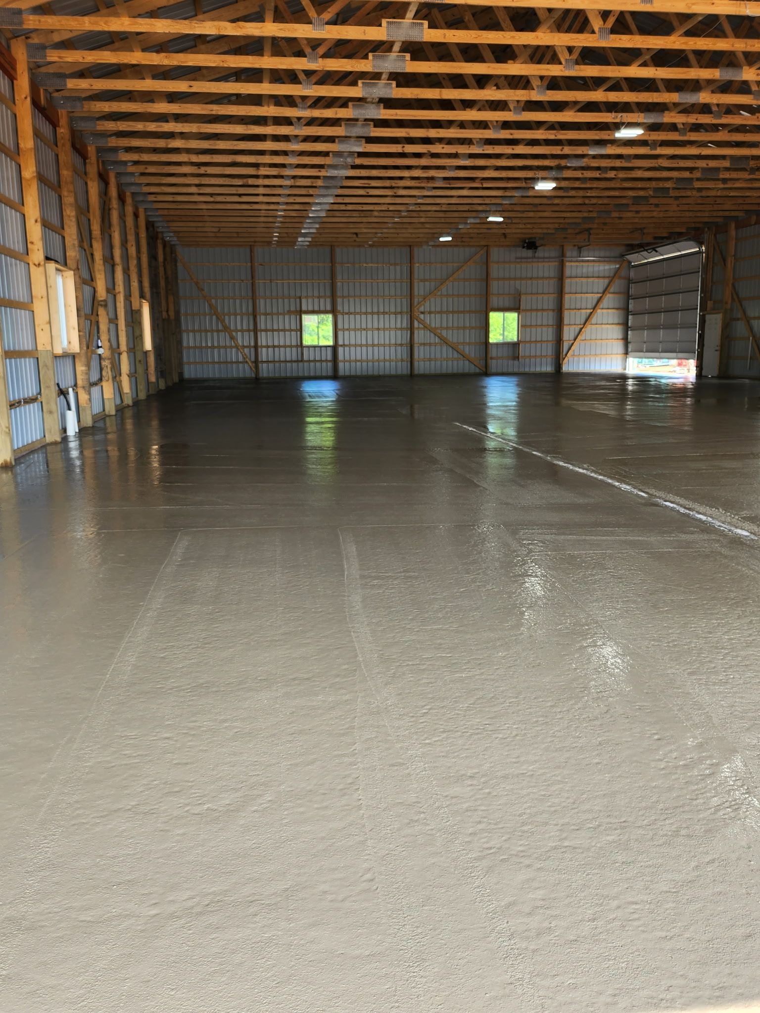 A large warehouse with a concrete floor and wooden beams.