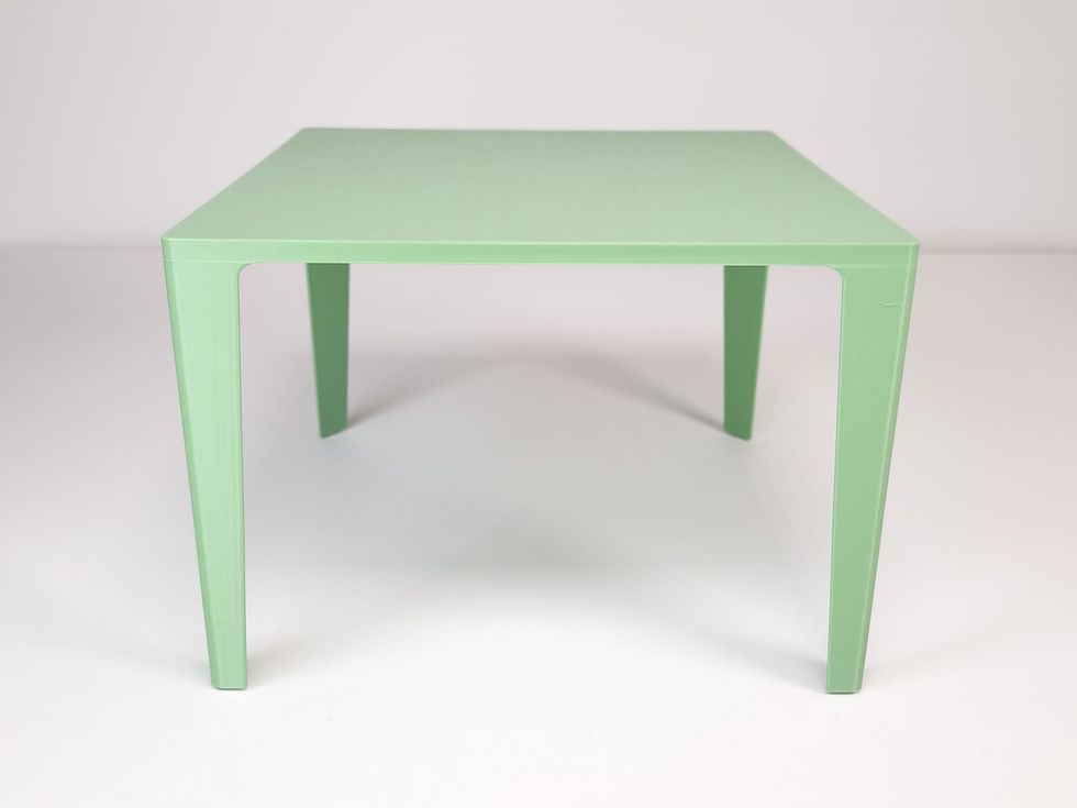 A simple, four-legged square table in a pale, solid green color, viewed from a slight front angle on a white background.