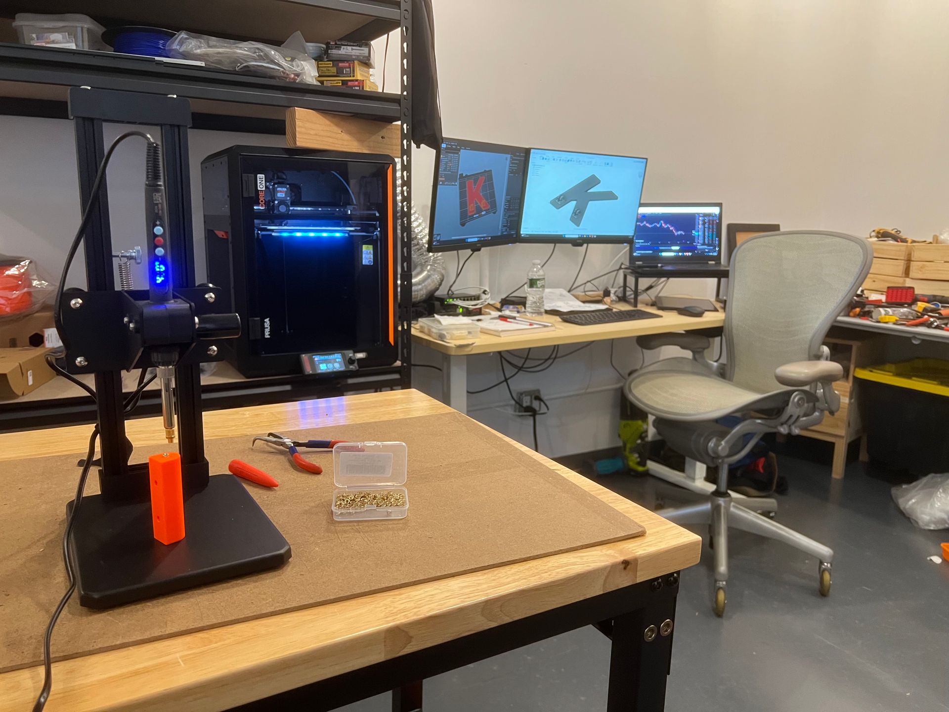 Our active 3D printing studio in Brooklyn NY, featuring a Prusa Core One printer on the workbench alongside our design station with dual monitors showing 3D models. This is where we create custom 3D printed household items and functional parts for customers across New York City and beyond — a real local Brooklyn 3D printing service in action.
